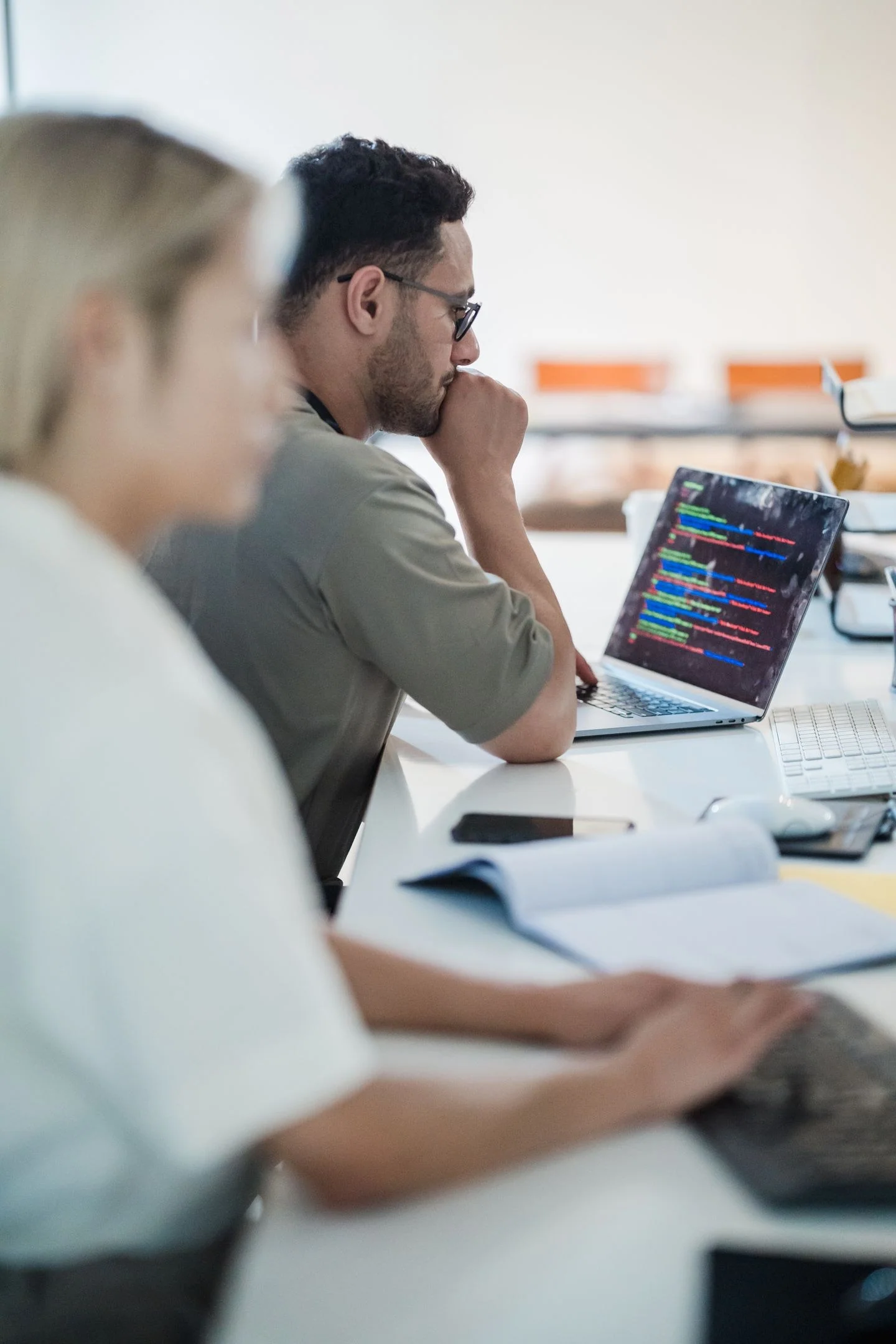 Two software developers work collaboratively on a coding project in a modern office setting.