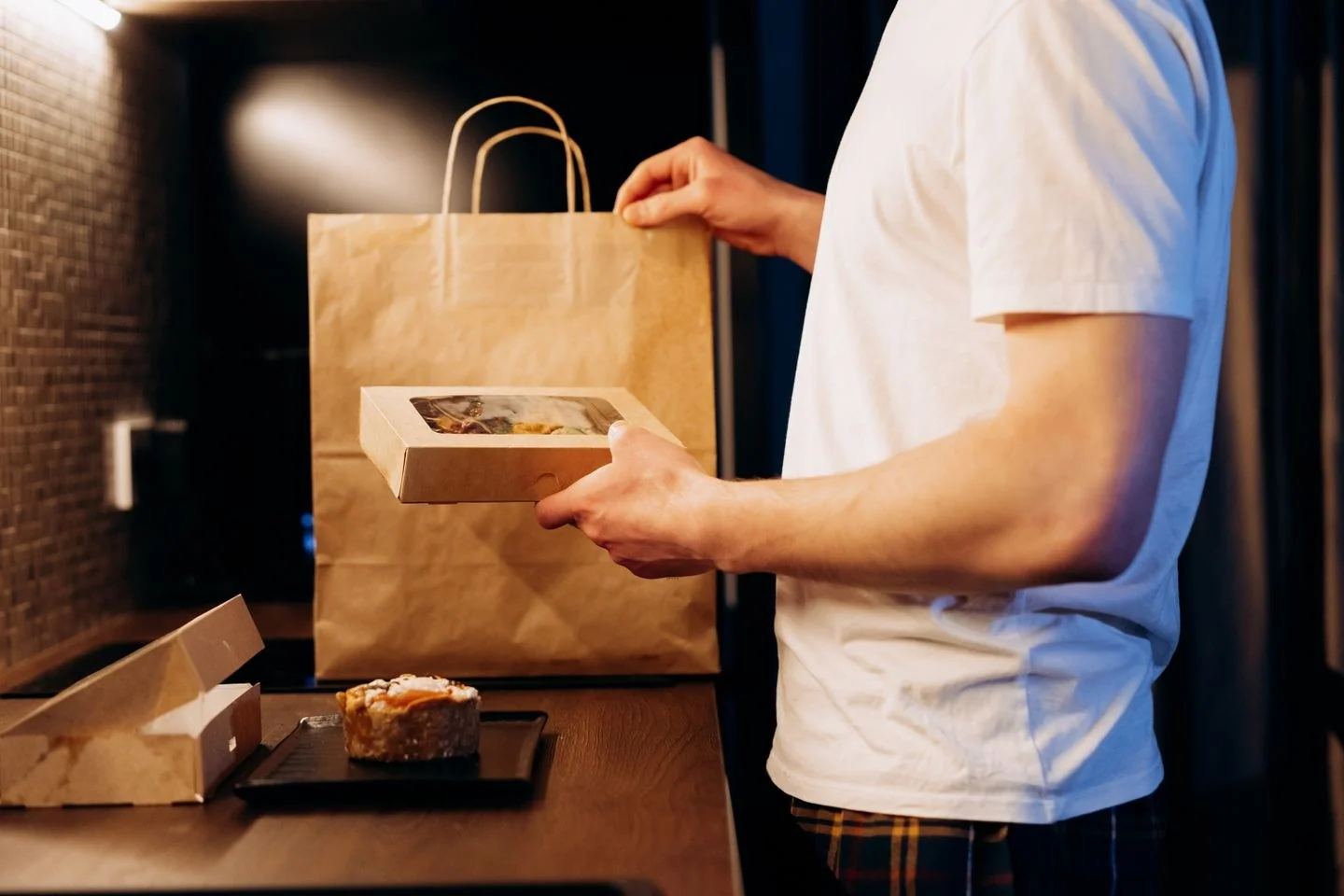 Man unpacking a food delivery bag in a modern kitchen. Ideal for lifestyle or delivery themes.