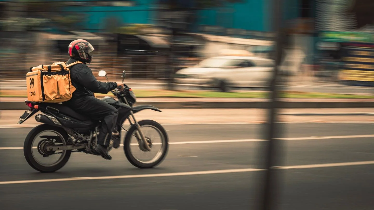 Motorcycle deliveryman speeds through city streets, showcasing fast food service.