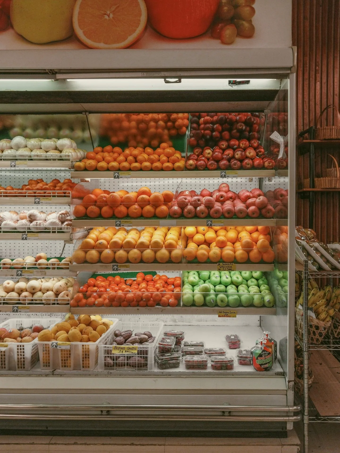 A vibrant selection of fresh fruits neatly arranged in a supermarket refrigerated display.