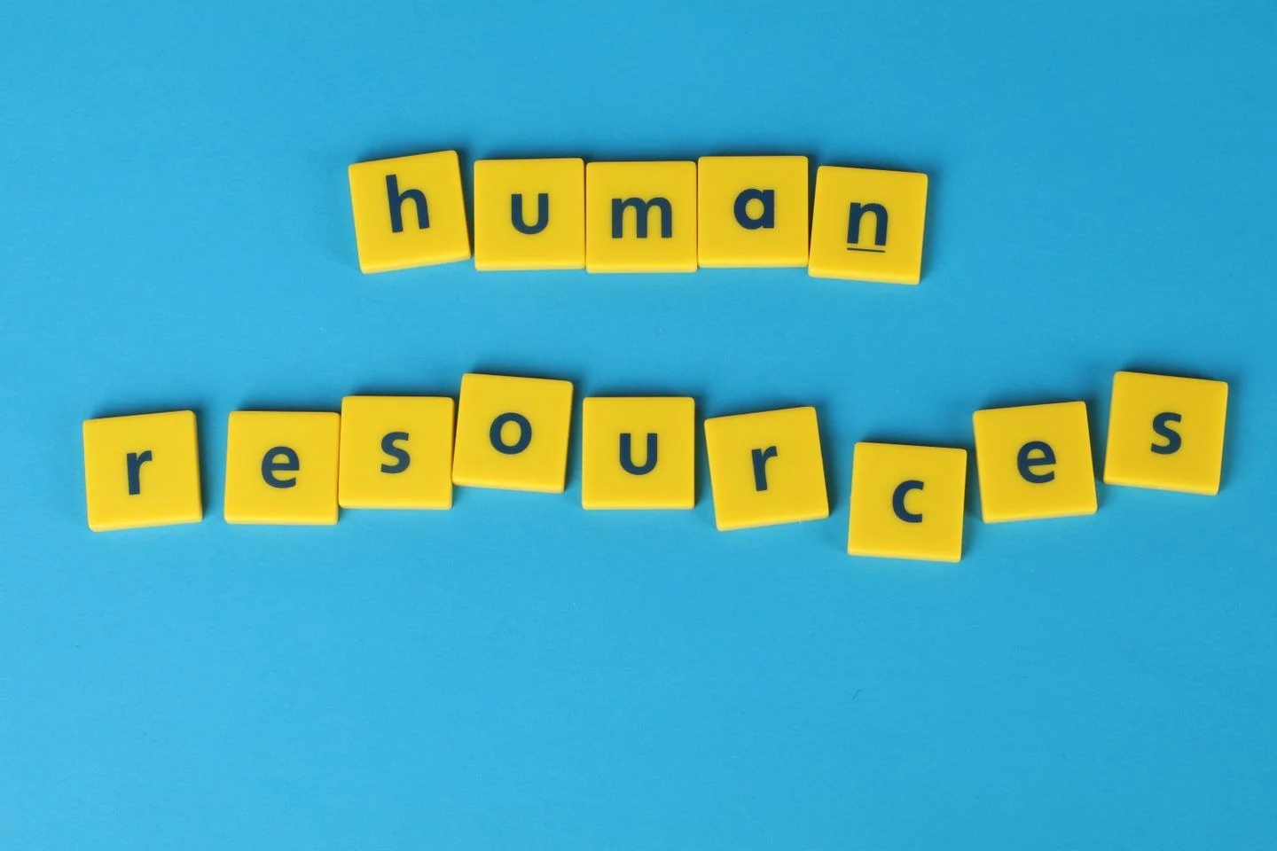 Yellow tiles spelling 'human resources' on a blue background, ideal for HR or business concepts.