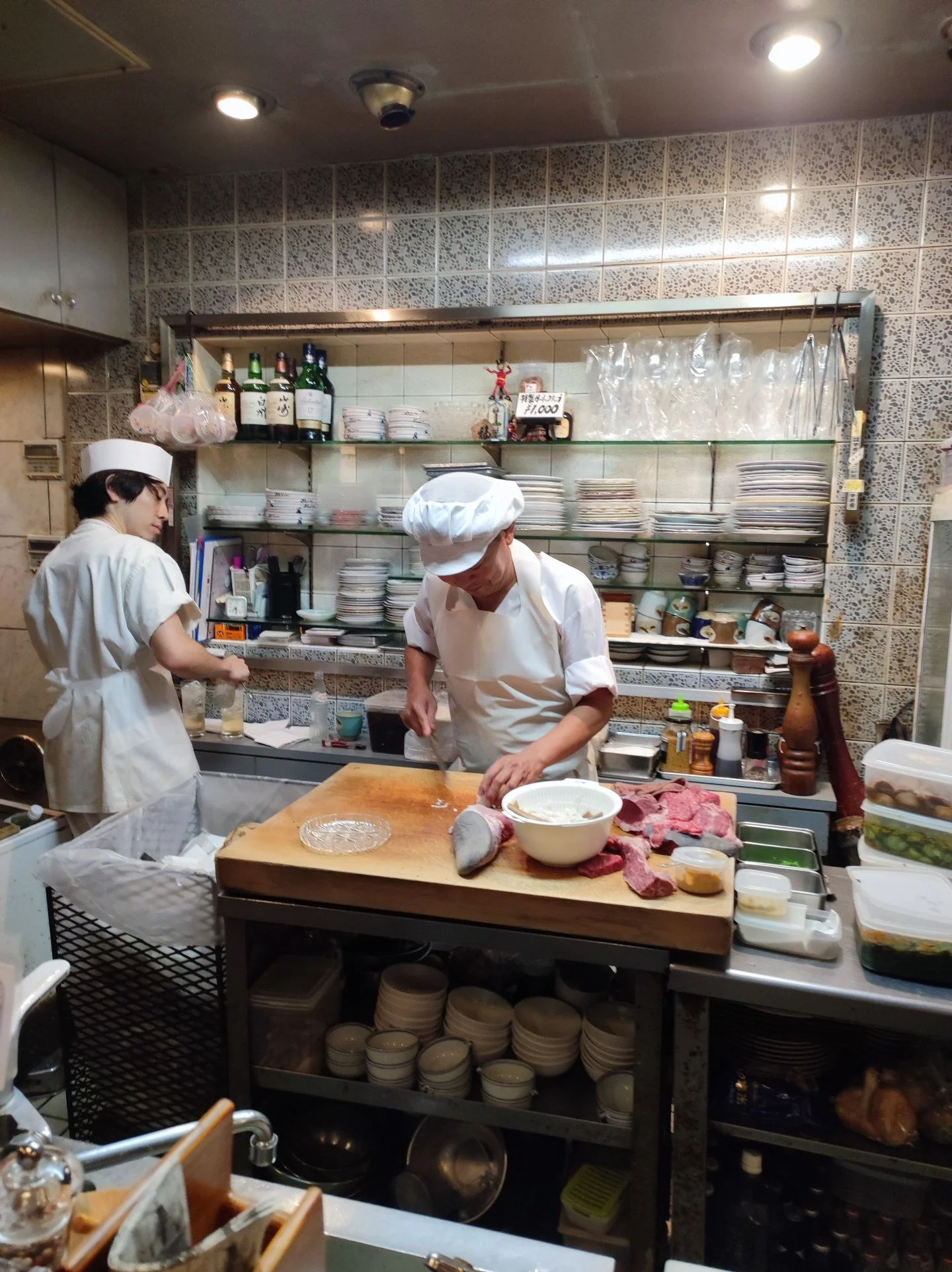 Two chefs skillfully preparing food in a bustling restaurant kitchen, surrounded by kitchenware.