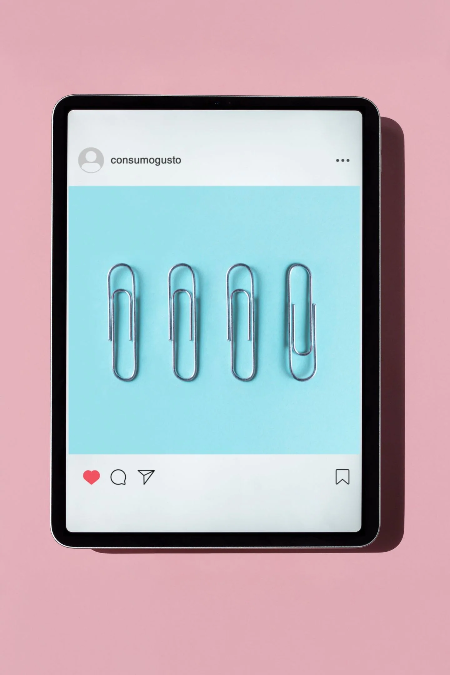 Tablet showing a social media post with paperclips on a pink background, ideal for digital gadget themes.