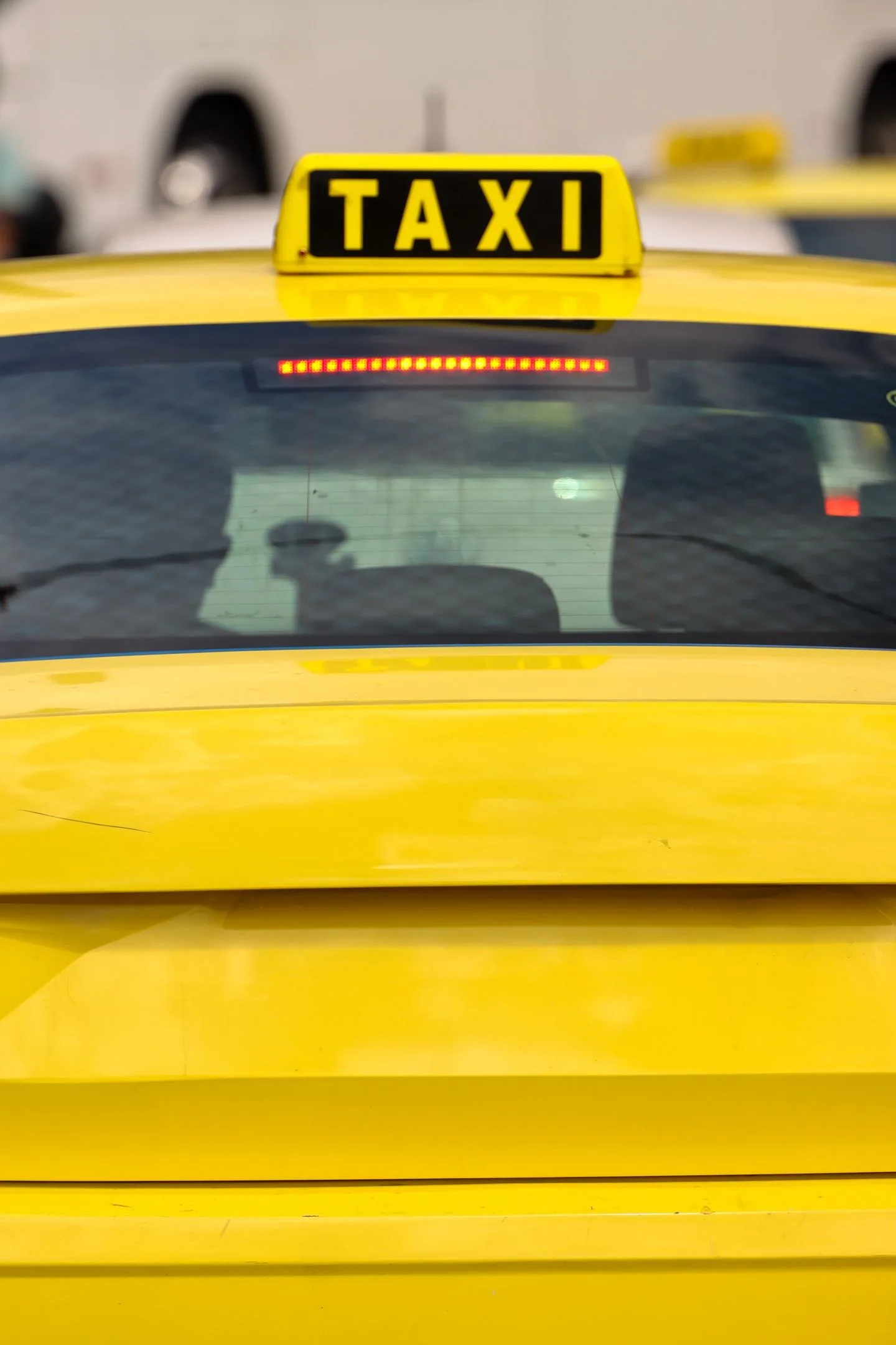 Close-up of a yellow taxi in Athens, Greece, highlighting the bright sign and urban setting.