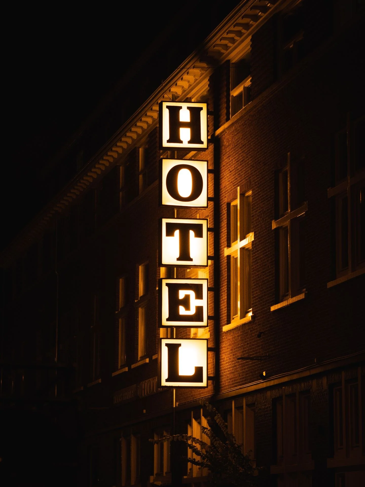 A bright hotel sign glowing on a building facade during nighttime.