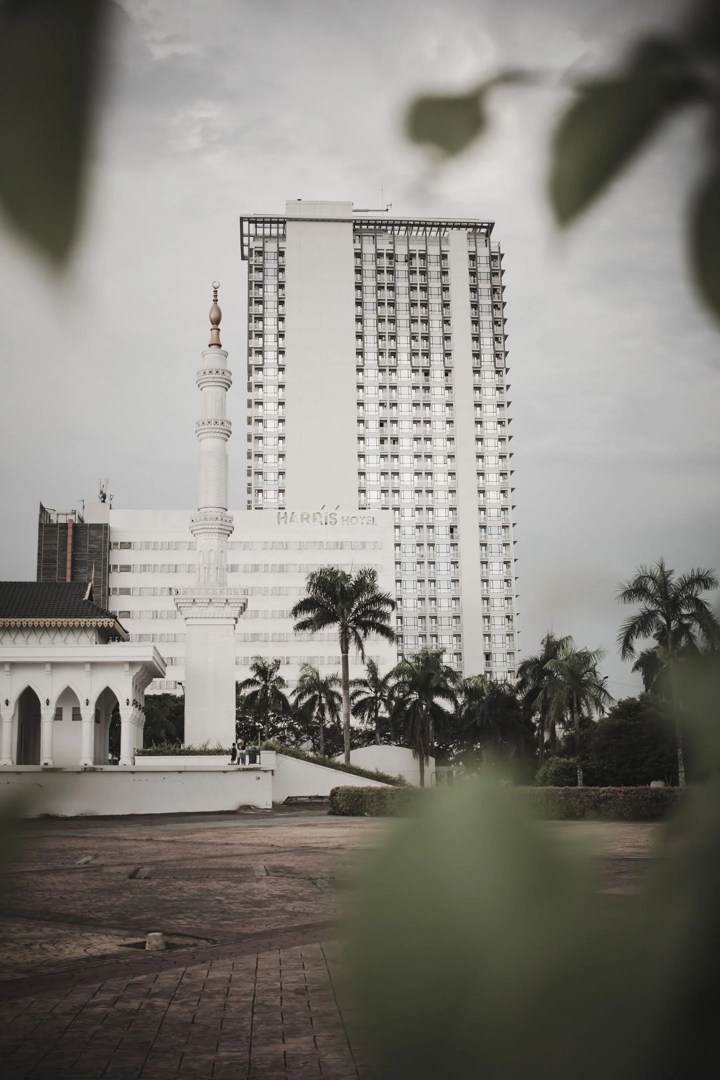 A modern high-rise building beside a mosque in Batam, showcasing urban Indonesian architecture.